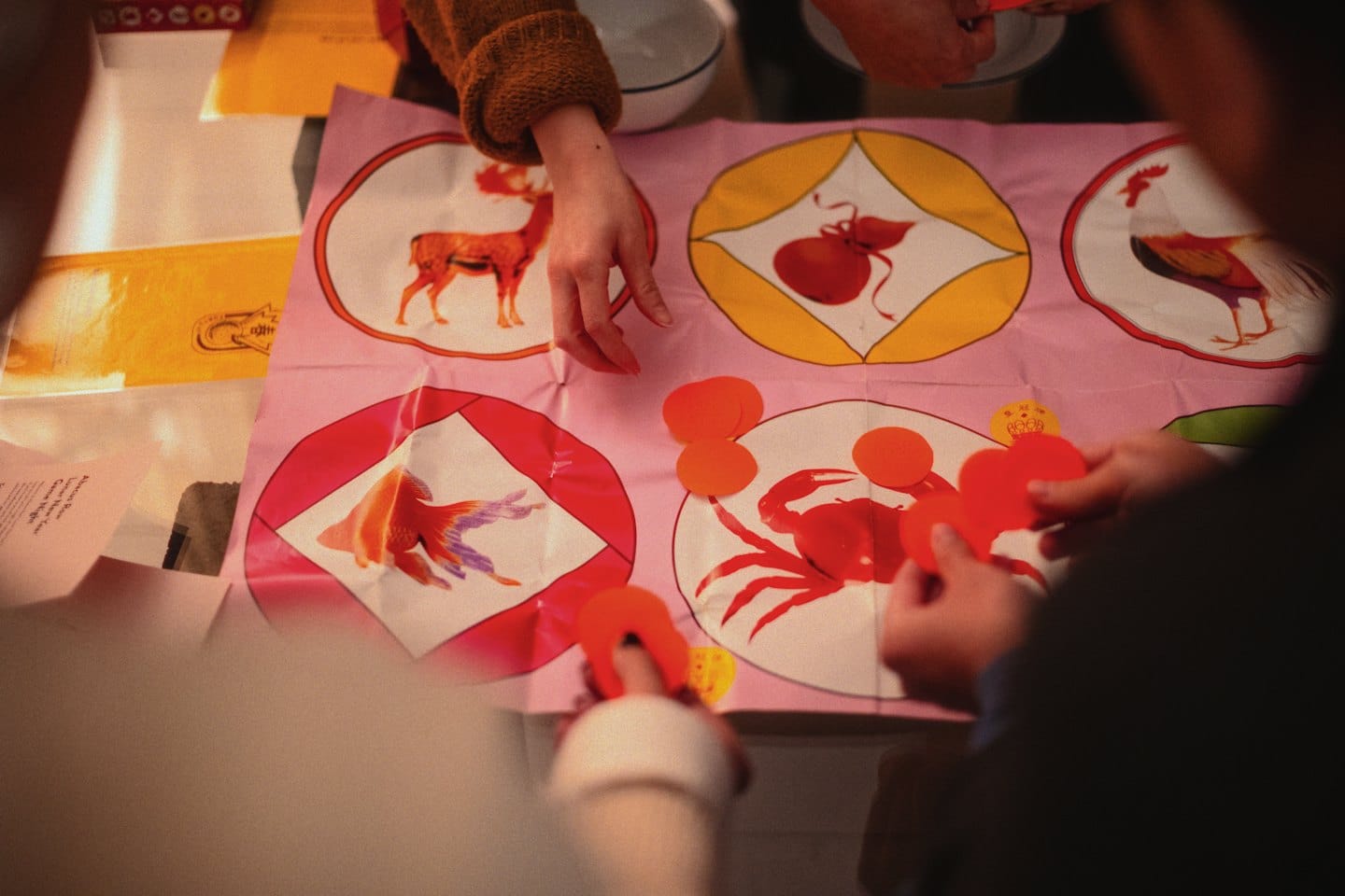 People playing a board game with colorful pieces on a mat.