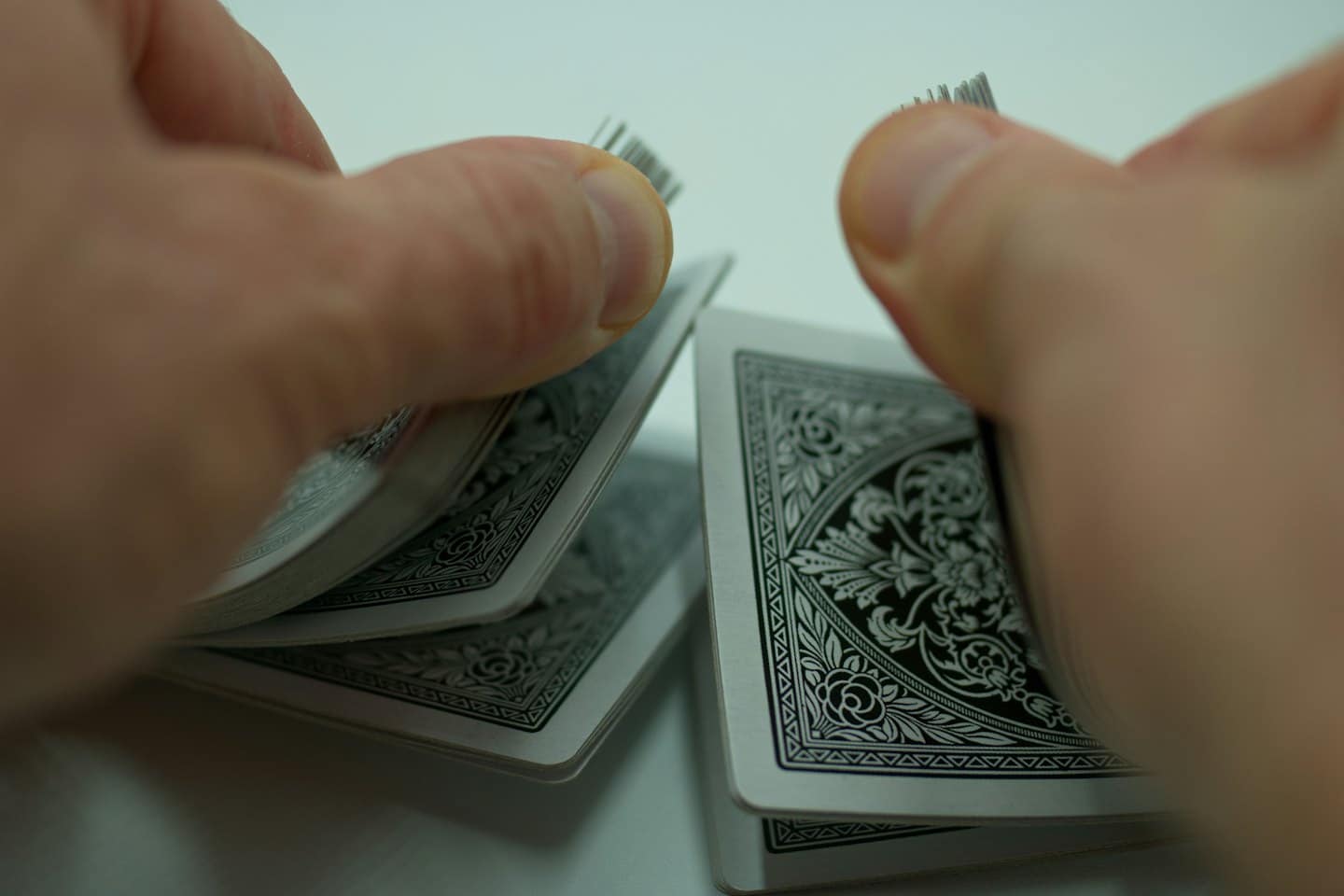 Two hands performing a riffle shuffle with playing cards.