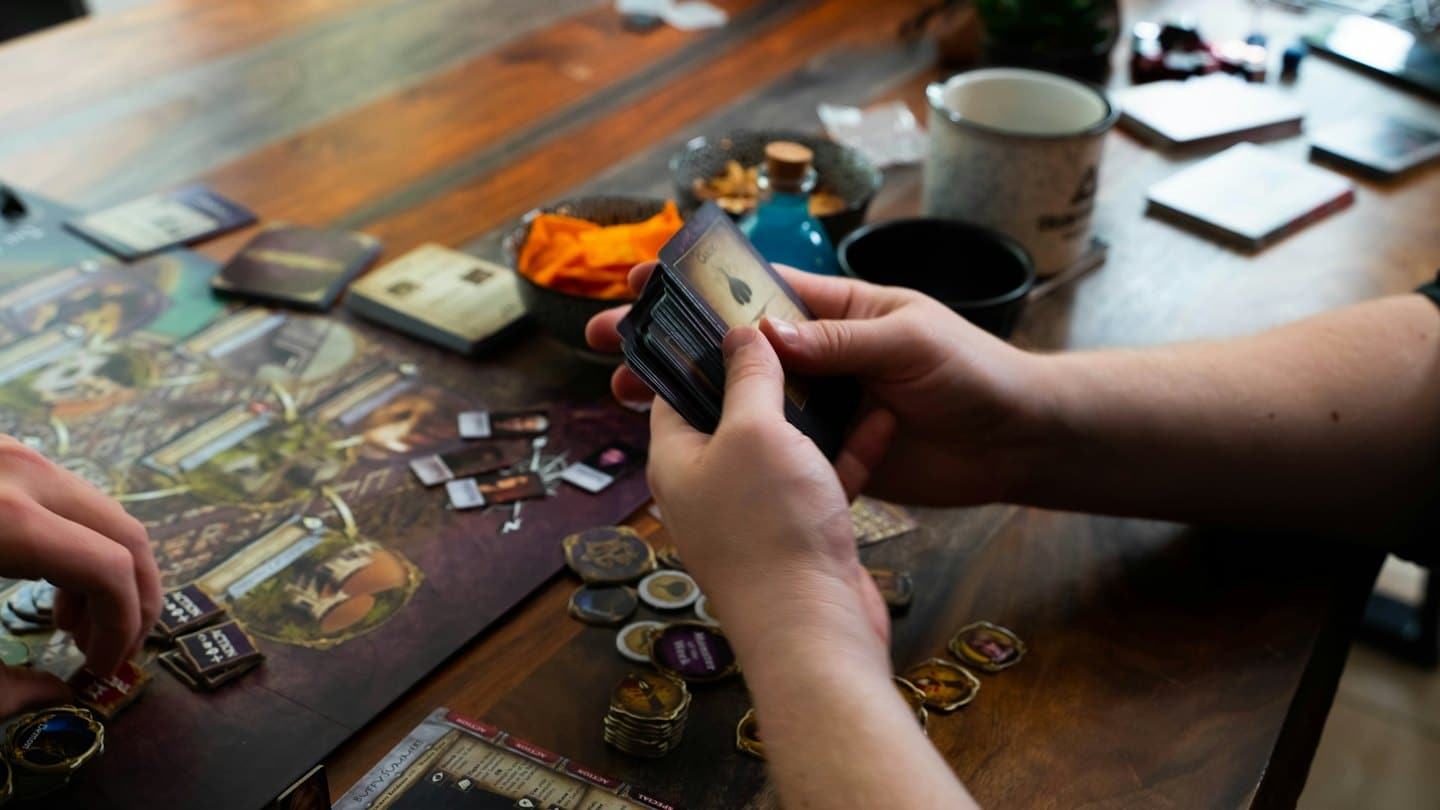 People playing a board game on a wooden table.